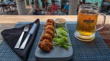 Un plato con pollo frito, una salsa acompañante y una cerveza en una mesa.
