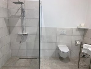 A modern bathroom with a glass-enclosed shower, a toilet, and a towel rack. - Apartment Panorama 2 near Airport (Elskop)