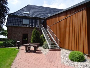 A two-story house with a brick facade, a wooden exterior wall, and a staircase leading to the upper floor. - Apartment Panorama 2 near Airport (Elskop)