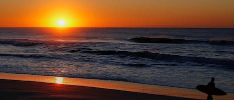 Perto da praia, areia branca, espreguiçadeiras, guarda-sóis 