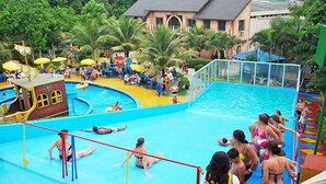 A swimming pool area with multiple lanes, palm trees, and a play structure.
