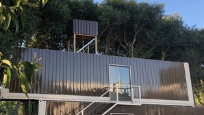 A modern, two-story building with a metal exterior and a glass door at the bottom. - Pousada Ondas de Floripa (Florianópolis)