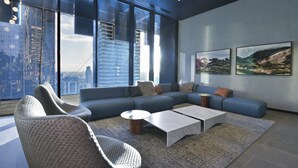 Una sala de estar moderna con un sofá modular, dos sillones, una mesa de centro y un ventanal con vistas a la ciudad.