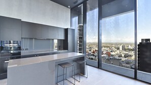 Una cocina moderna con una isla grande y taburetes de bar, ventanas amplias con vistas a la ciudad.