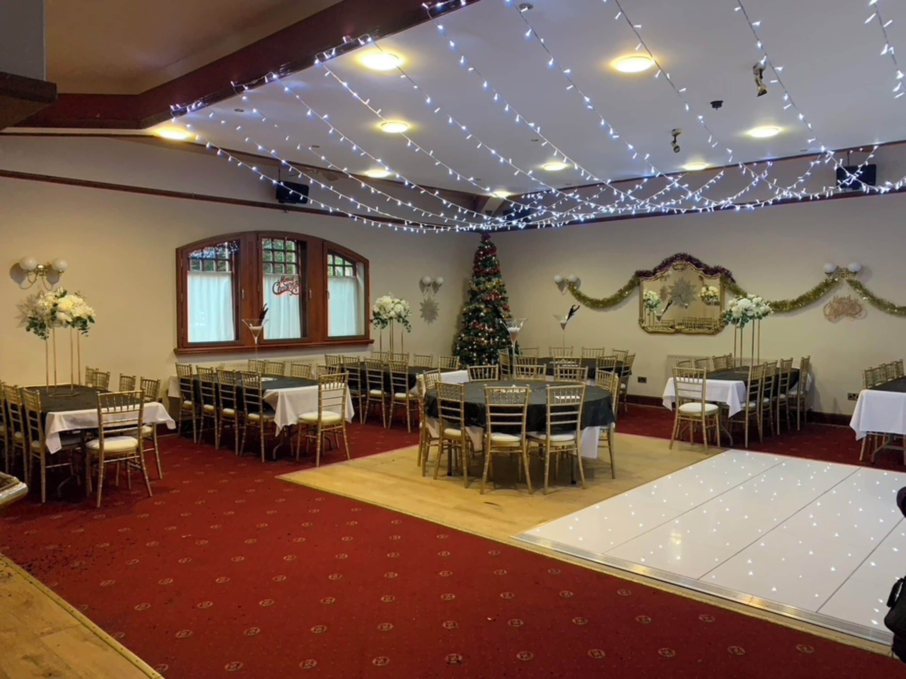 Un salón de banquetes con mesas redondas, sillas y una pista de baile.