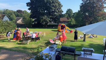 Ein Garten mit Grillmöglichkeit, Picknicktischen und einem Spielbereich für Kinder.