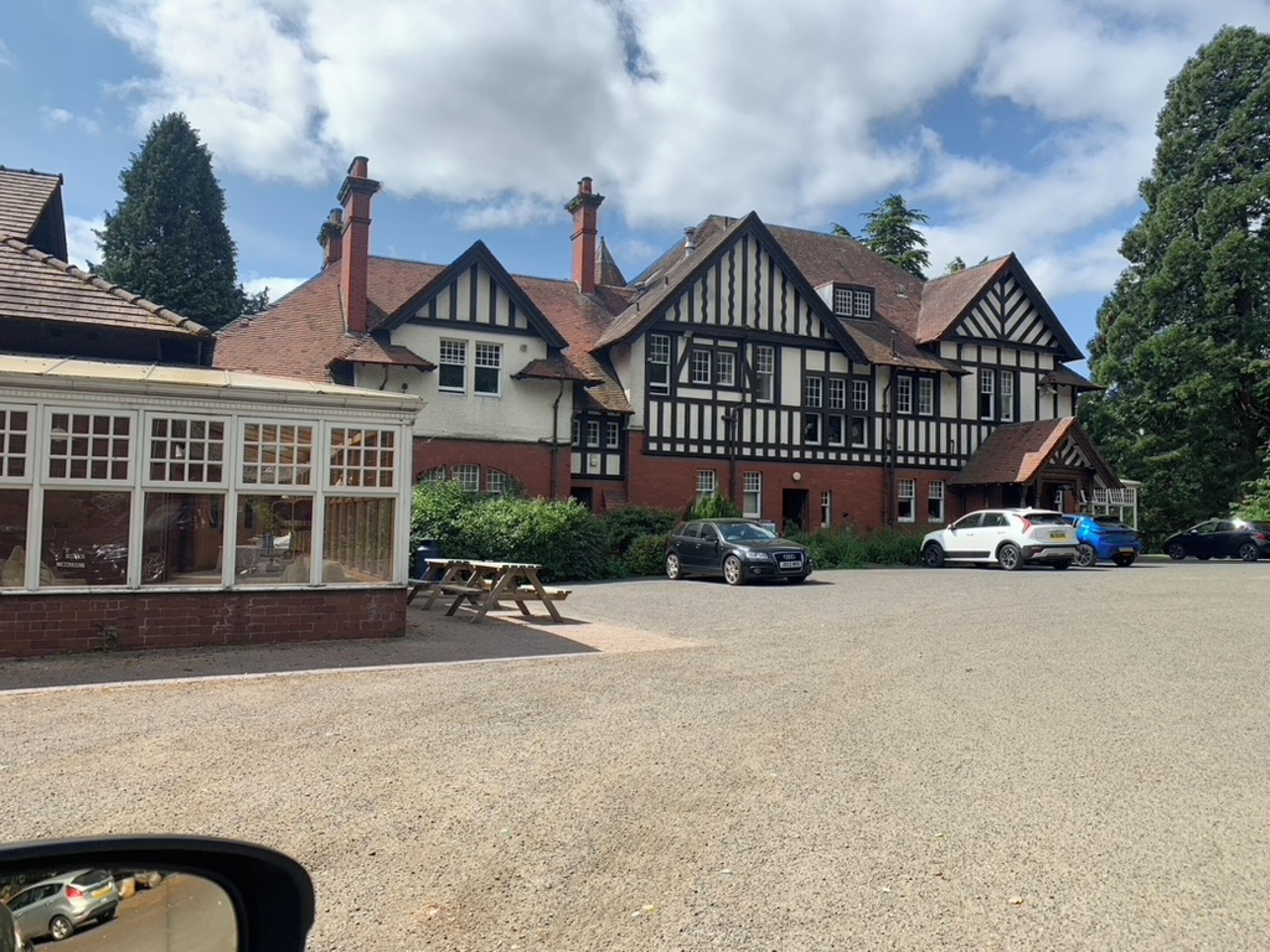 Un edificio de estilo Tudor tradicional con múltiples chimeneas y un aparcamiento de grava.