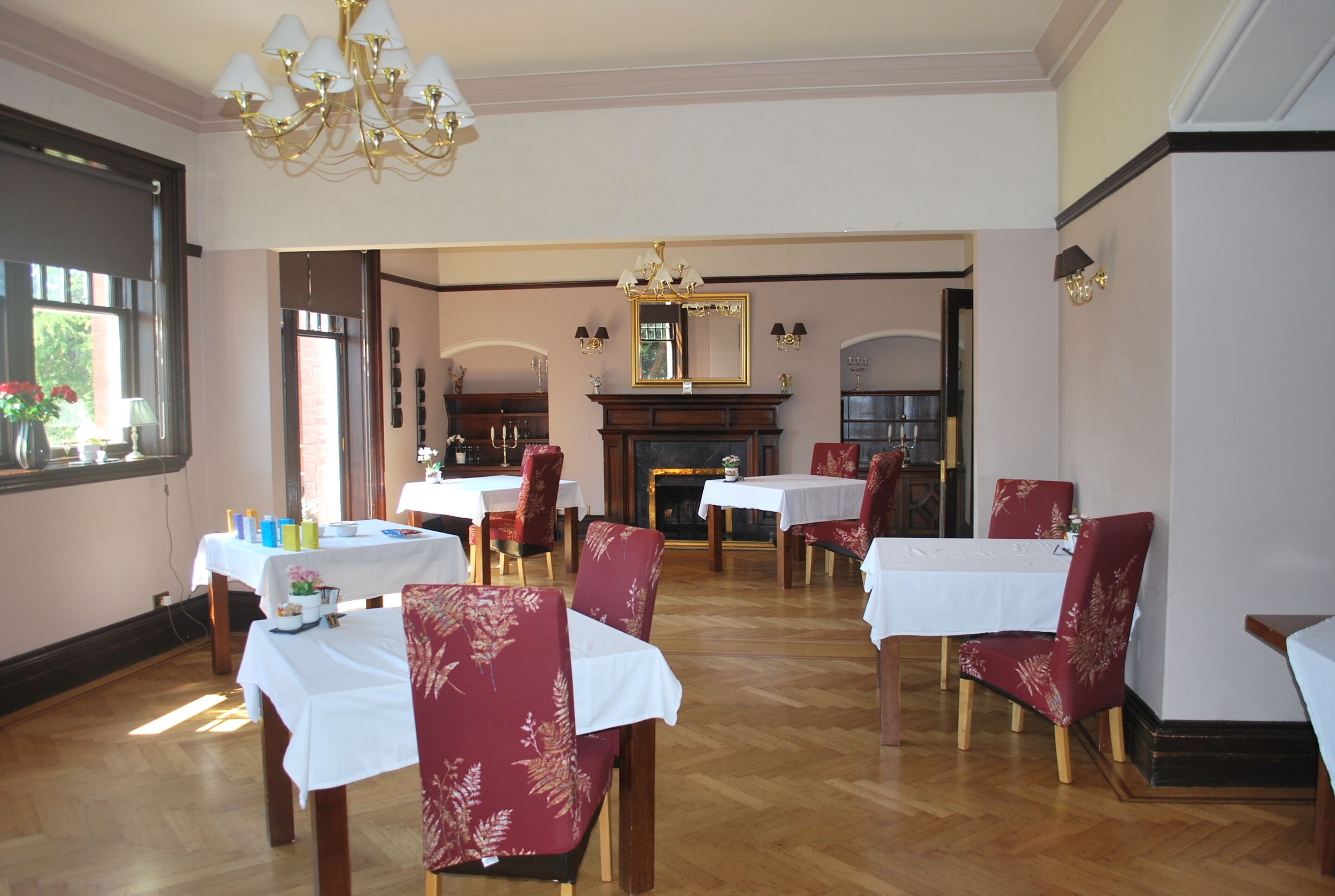 A dining area with tables and chairs, a chandelier, and a fireplace.