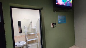 Een badkamer met toilet, wastafel en een aan de muur bevestigde televisie.