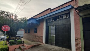 Een gebouw met een bord waarop 'HOTEL LATINO' staat en een hekwerk.