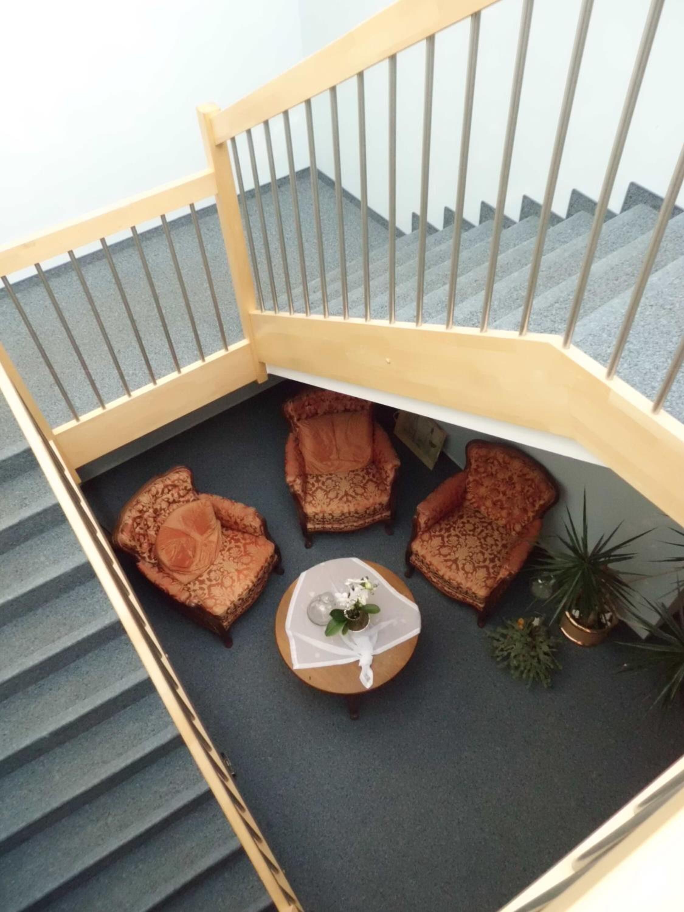 A corner seating area with four patterned chairs and a small round table with a vase of flowers.