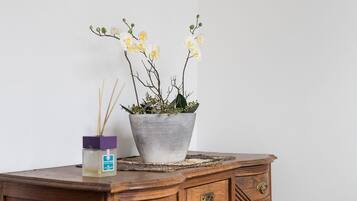 Un aparador de madera con una orquídea en maceta y un difusor de cañas.