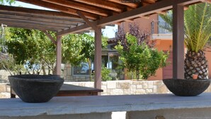 Un espacio al aire libre cubierto, con paredes de piedra y grandes macetas.
