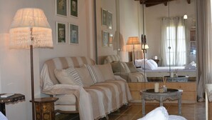 Una habitación de hotel acogedora con una cama grande, un sofá, una mesita con una vela y un espejo que refleja la habitación.