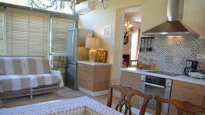 Una sala de estar acogedora con un sofá, una mesa de comedor con sillas, una cocina con estufa, refrigerador y chimenea.