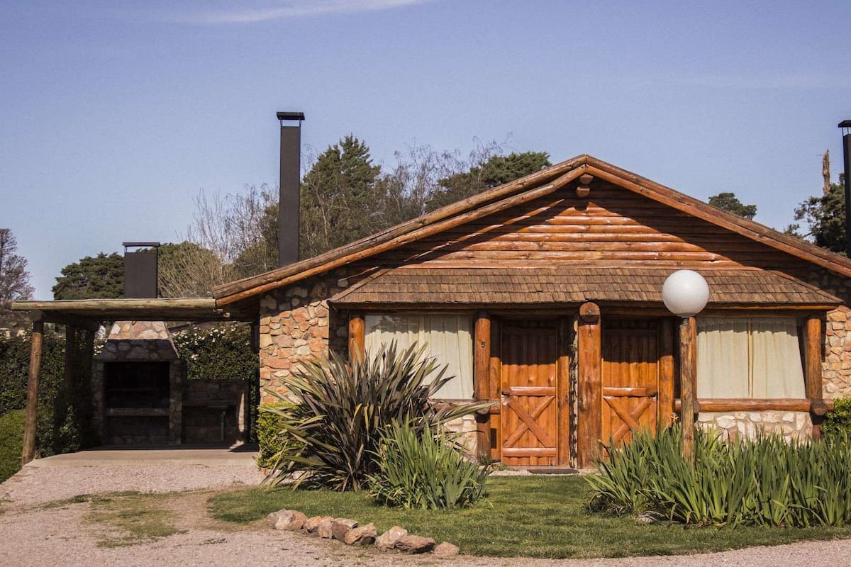 Une cabane rustique en rondins de bois, avec une façade en pierre, une porte d’entrée en bois et une cheminée.