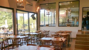 A restaurant with wooden tables and chairs, large windows, and hanging light fixtures. - Balcon del Golf Resort, Spa & Restaurant. (Sierra de la Ventana)