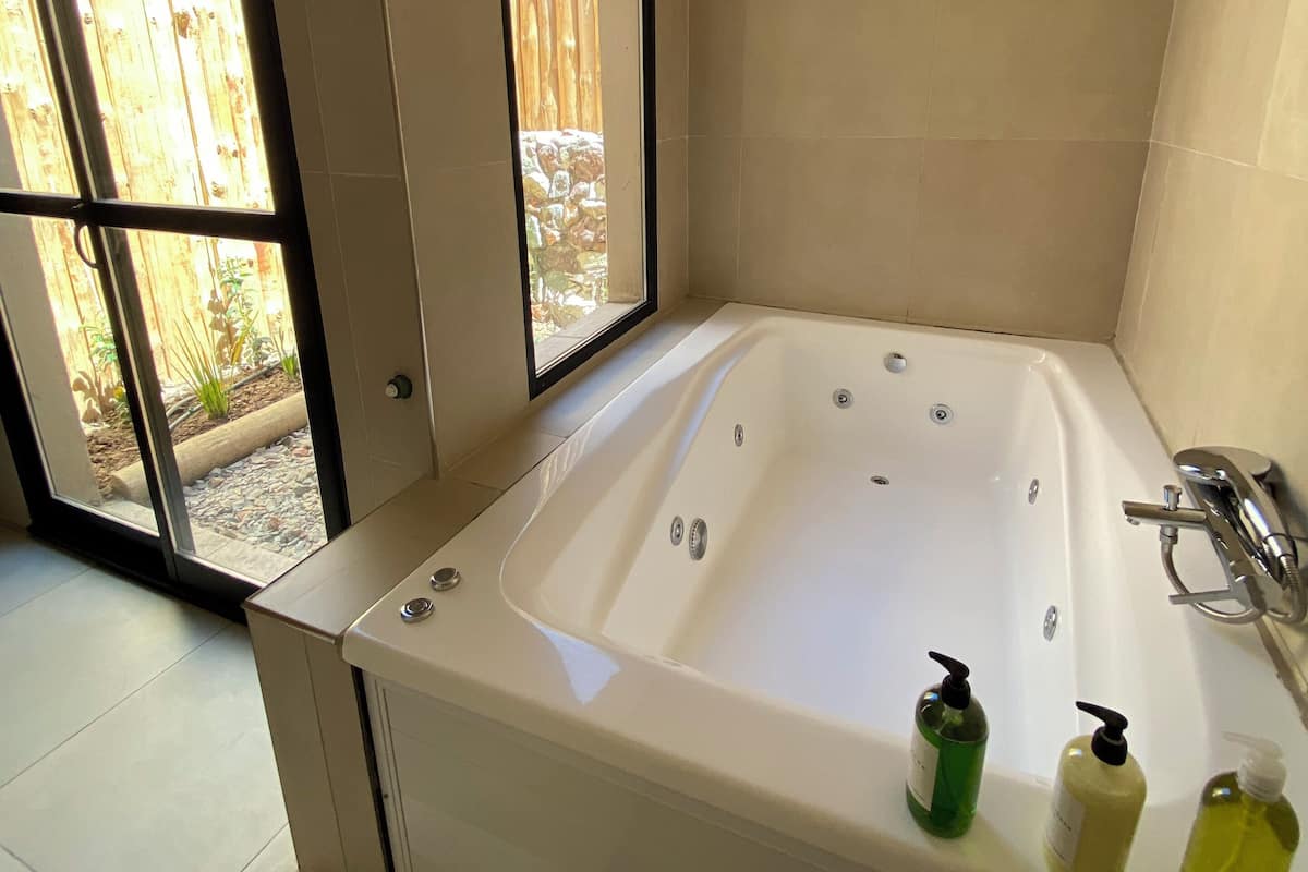 Une salle de bain moderne avec une grande baignoire, une fenêtre et une vue sur une clôture en bois.