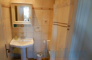 Une salle de bain équipée d’un lavabo, d’un miroir, de toilettes et d’un rideau de douche.