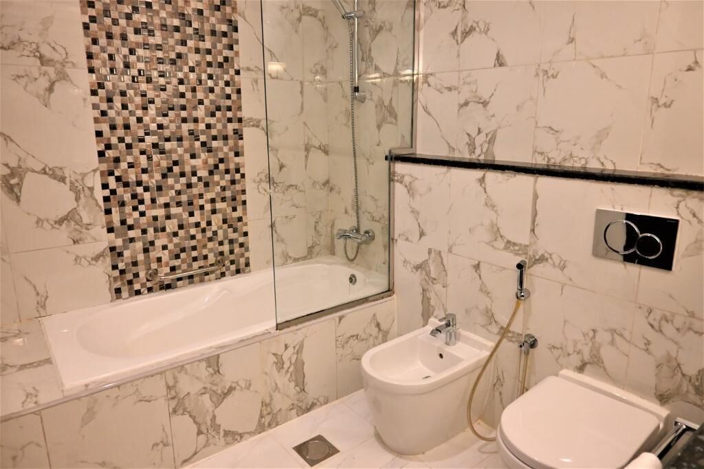 A modern bathroom with a glass-enclosed shower, a freestanding bathtub, a bidet, and a toilet.