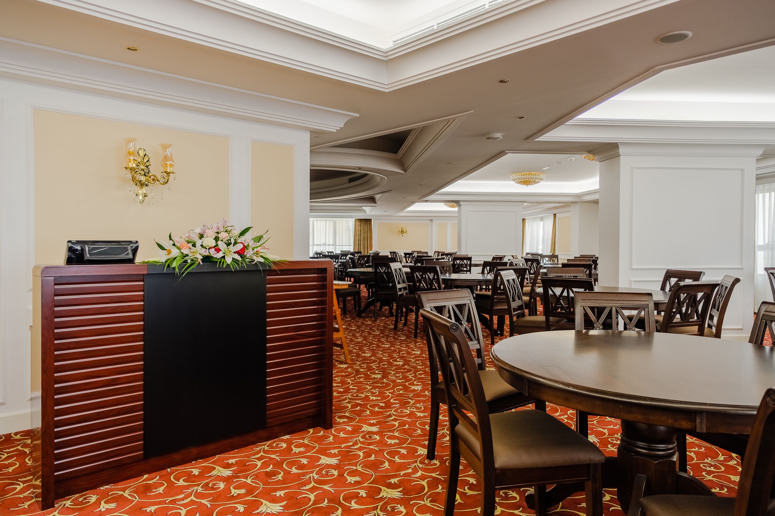 A hotel lobby with a reception desk, multiple dining tables, and chairs.