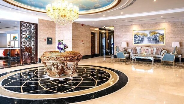 Eine Lobby mit einem zentralen, verzierten Tisch, einer Kristallleuchter, einer Sofagarnitur und einem Gemälde an der Wand.