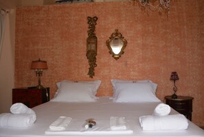 Een hotelkamer met een groot bed, twee kussens, een spiegel en twee nachtkastjes met lampen.