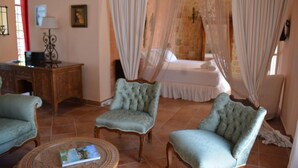 A room with a bed, two armchairs, a small table, and a desk. - Alekos Beach Houses - Natura Rossa (Kefalonia)