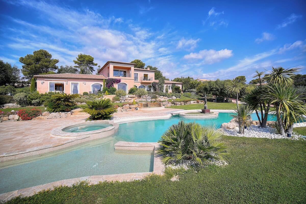 A large house with a swimming pool and lush landscaping.