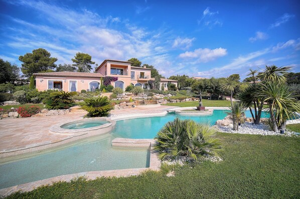 Una casa grande con piscina y jardines exuberantes.
