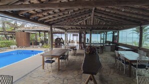 A covered outdoor area with a pool, tables, and chairs. - PRIS Hotel (São Sebastião)
