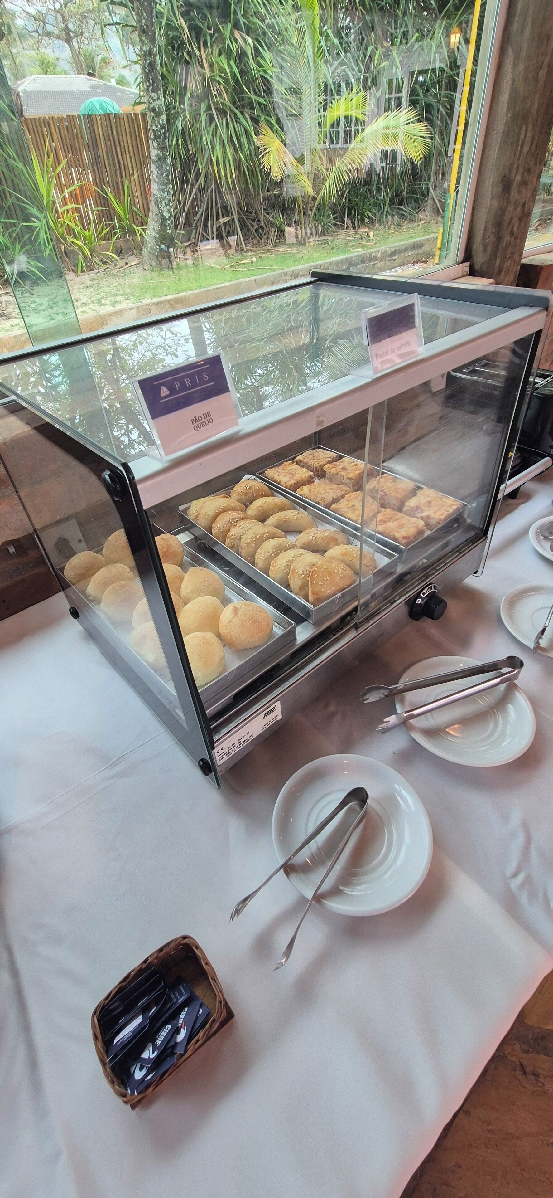 A bakery display case with pastries and a sign indicating 'Pão de Queijo'.