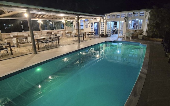 Una piscina con asientos exteriores cercanos y un área cubierta, presumiblemente para comer o relajarse.