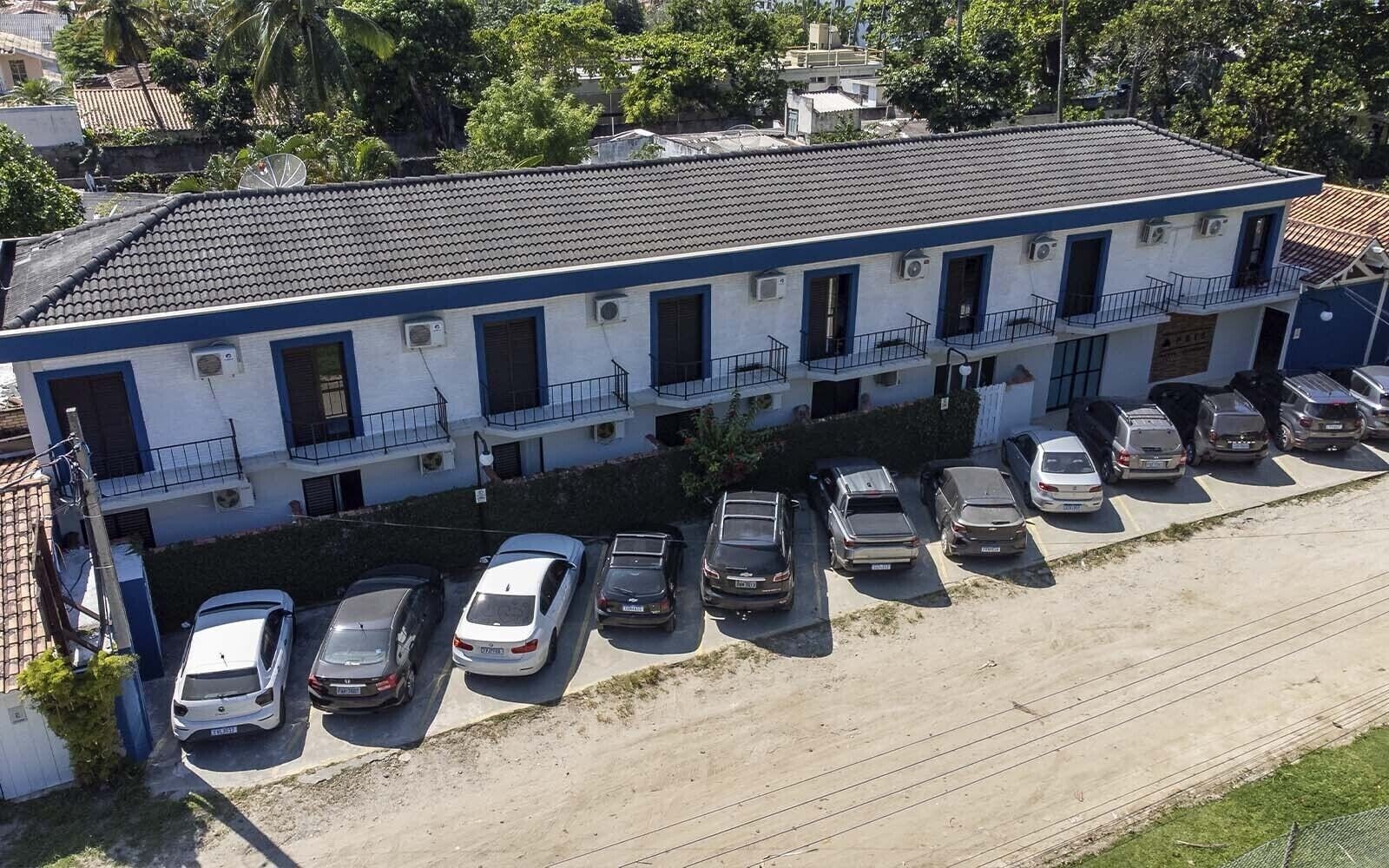 A two-story building with a row of parked cars in front.