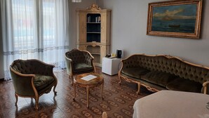 A room with a chandelier, a painting, a cabinet, and two sofas. - Villa Ada B&B (Agropoli)