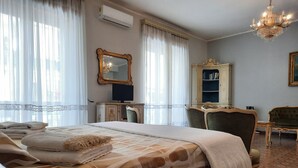 A hotel room with a large bed, a desk with a computer, a chair, a wardrobe, and a chandelier. - Villa Ada B&B (Agropoli)