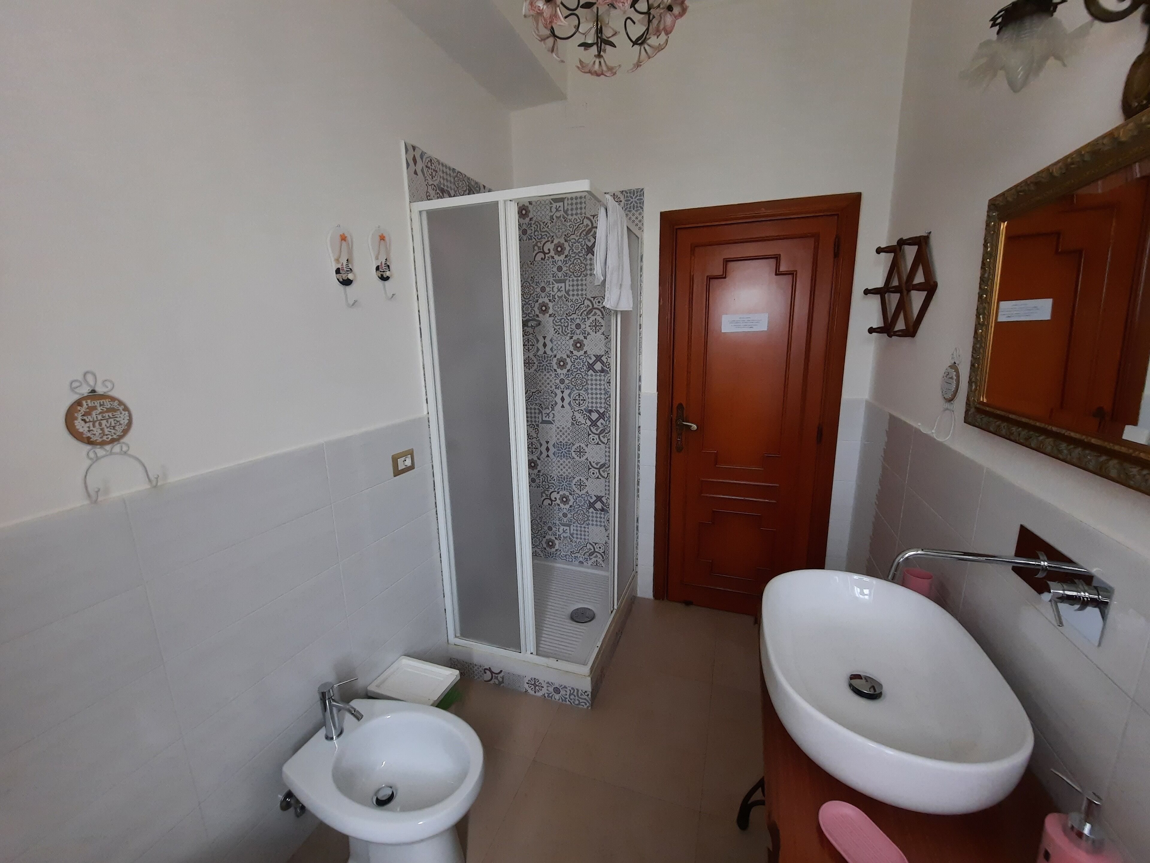 Un bagno con lavandino bianco, bidet, cabina doccia e porta in legno.
