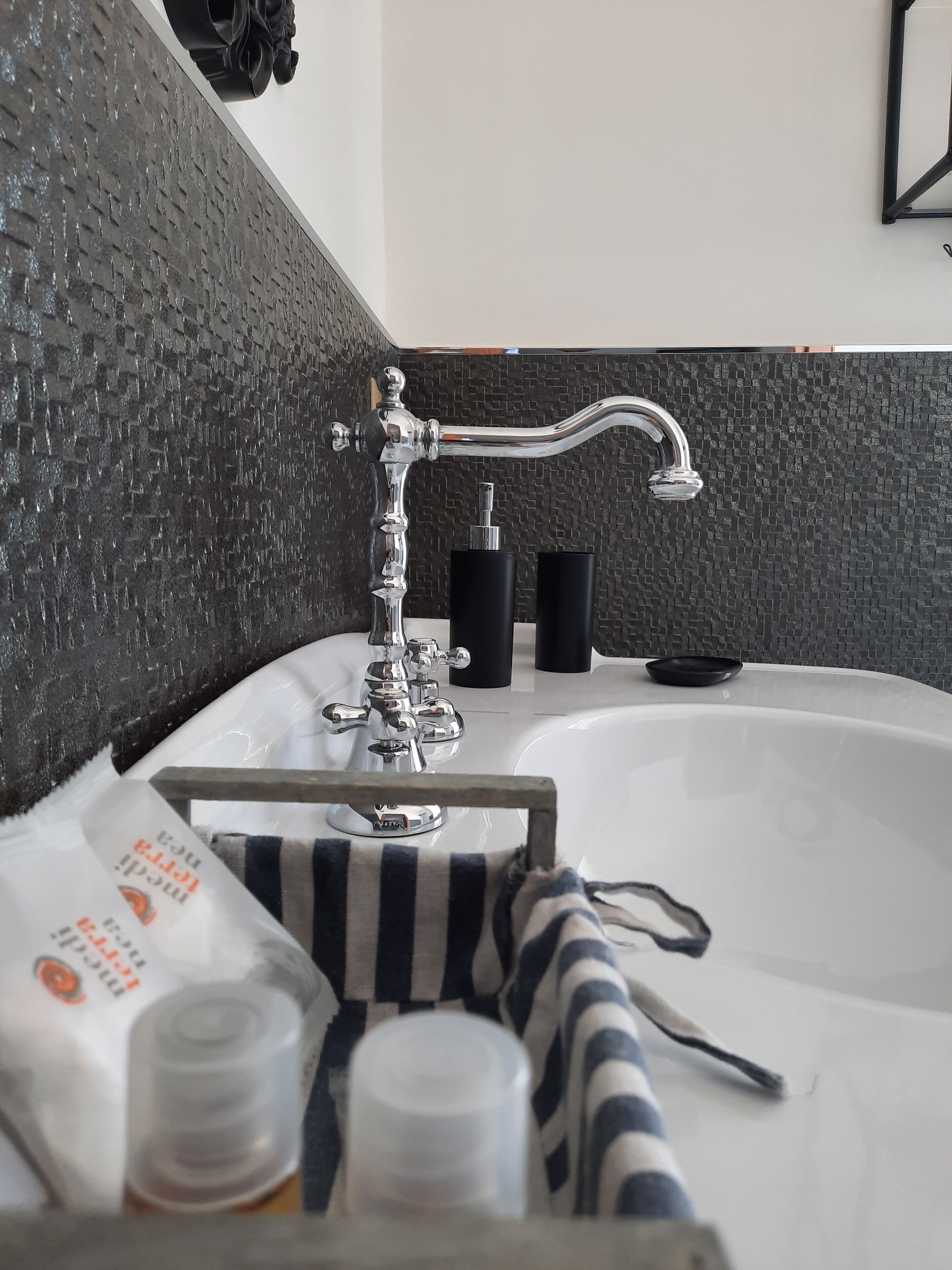 Un baño con una bañera grande, un grifo moderno y artículos de aseo a un lado.