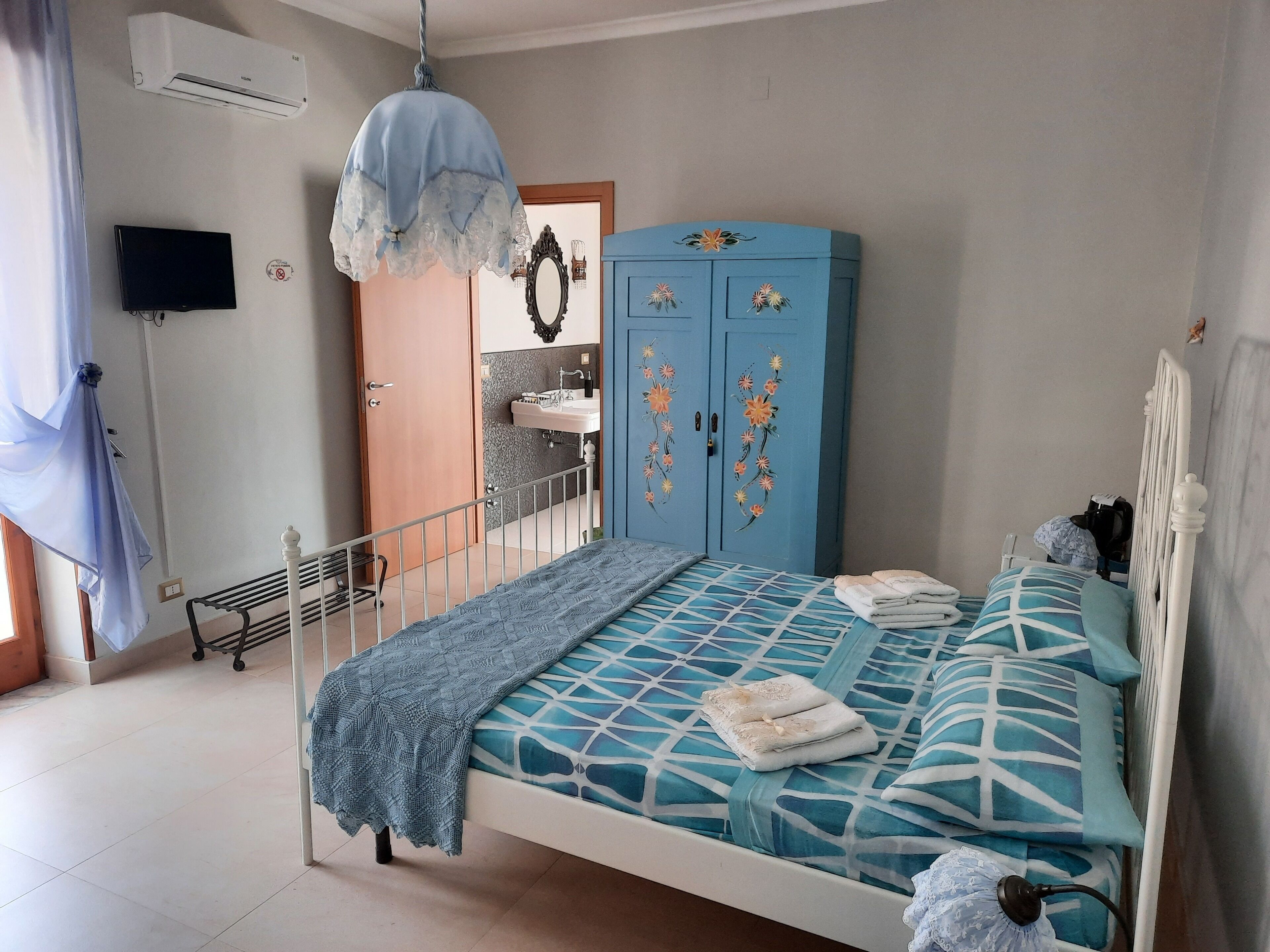 A bedroom with a bed, a wardrobe, a sink, and an air conditioner.