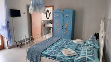 A bedroom with a bed, a wardrobe, a sink, and an air conditioner.