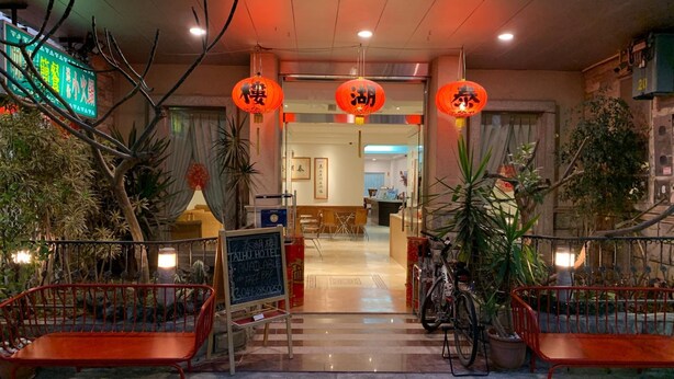 L’entrée d’un hôtel, avec un comptoir d’accueil, une enseigne et un vélo garé à l’extérieur.