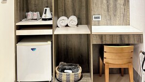 Une pièce de taille modeste, comprenant une armoire en bois, un petit réfrigérateur, un panier en osier et une chaise en bois.