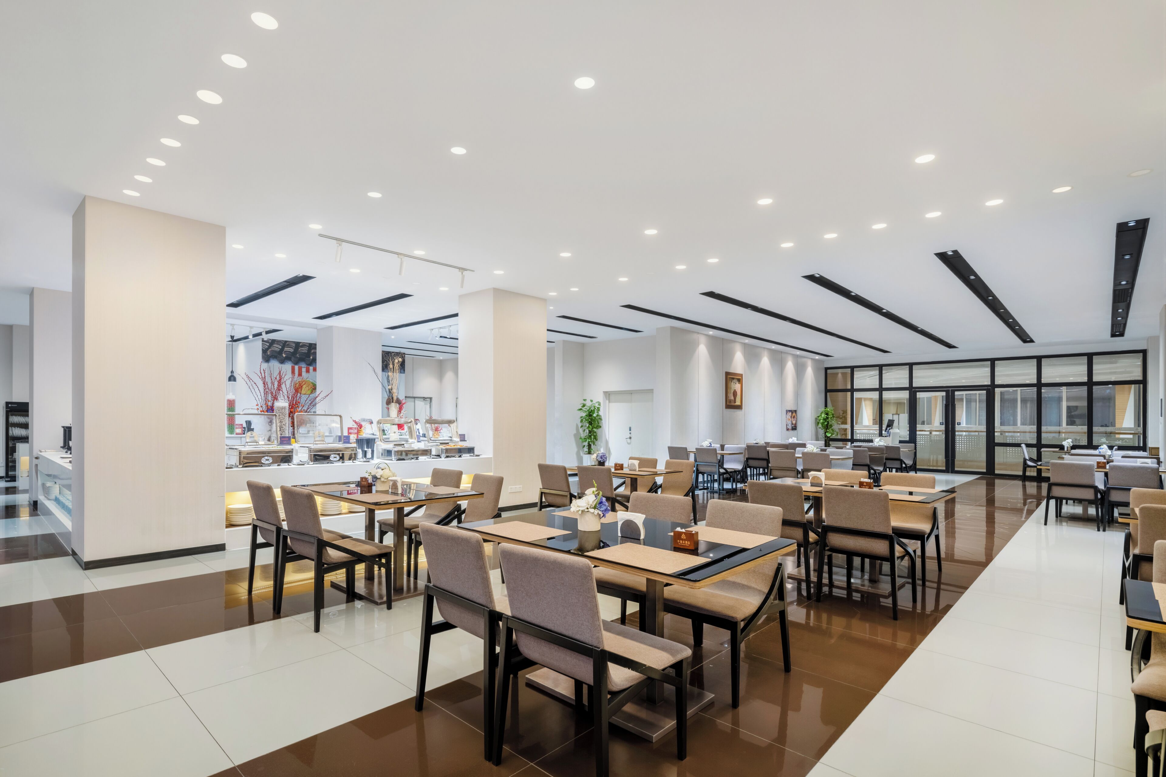 Un comedor moderno con mesas y sillas, una barra con artículos, y un ventanal grande.