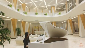 A modern hotel lobby with a central seating area, multiple levels, and potted plants.