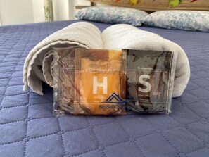 Two shampoo bottles on a bed with a blue quilted cover. - Apartamento Jurere Internacional (Florianópolis)