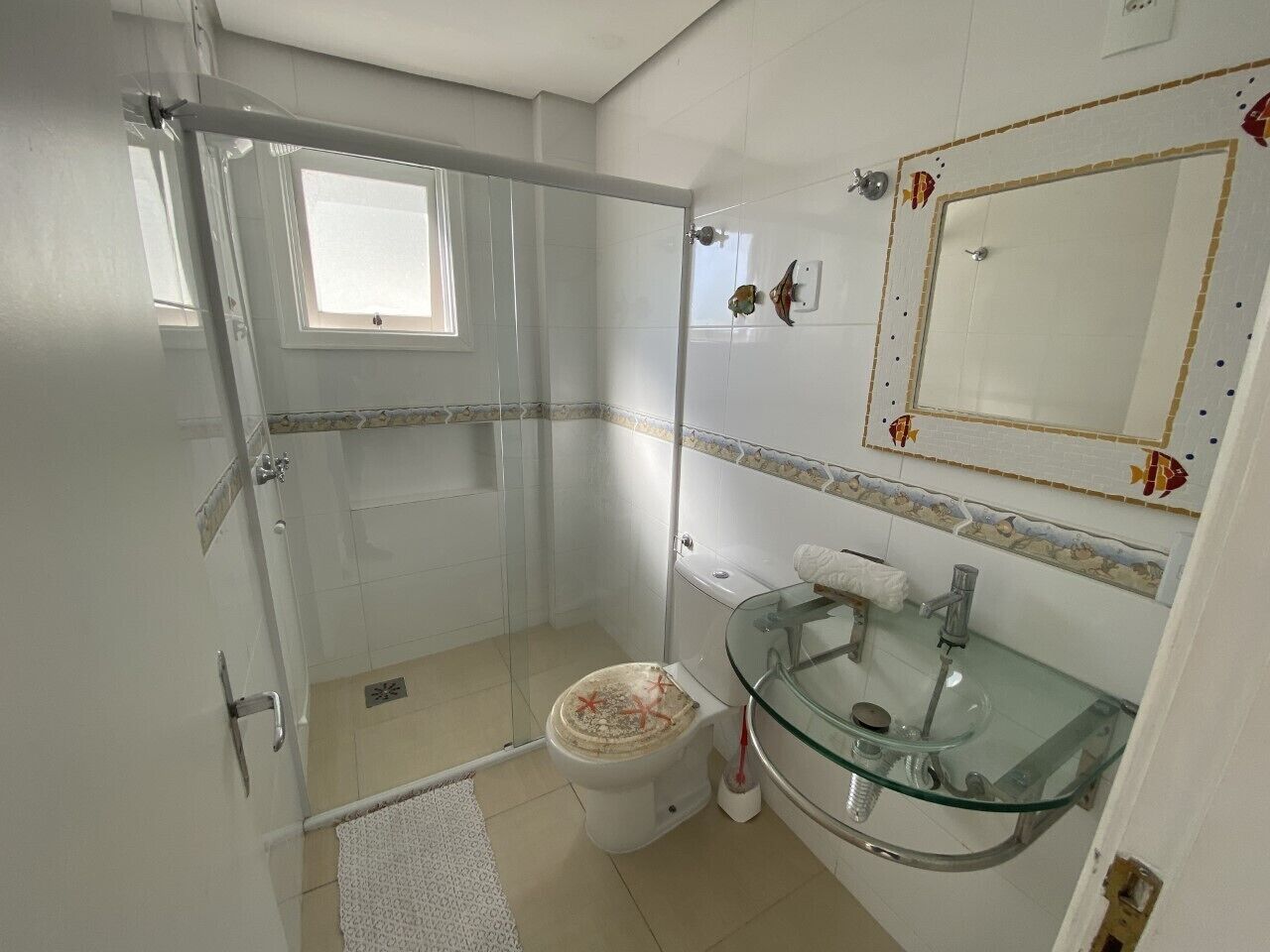 A bathroom with a glass shower enclosure, a toilet, and a glass sink with a mirror above it.