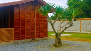 Un edificio de madera con techo inclinado y un pequeño árbol en la parte delantera.