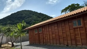 Una construcción de madera con techo de tejas, rodeada de grava y una palmera.