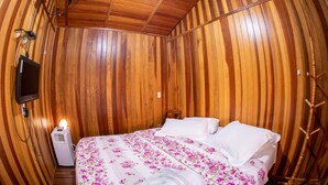 Una habitación con paneles de madera, una cama, un televisor y un calentador.