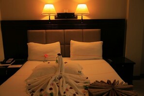 Une chambre d’hôtel avec un lit, deux lampes de chevet, un téléphone et une composition décorative sur le lit.